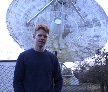 Student standing in front of satellite 