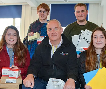 Four students with Managing Partner from Chrisbeon holding stationery that they will take to Ghana