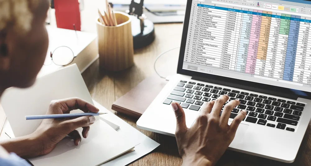 Close up of a person on a laptop working on a spreadsheet.