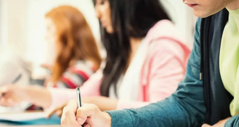 Close up of students in classroom writing notes