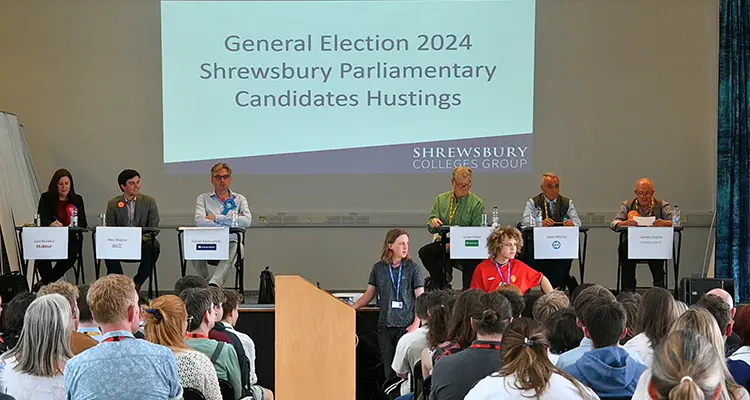 Group picture of all hustings candidate's on stage with crowd of students facing them 