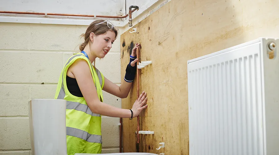 Student fixing pipes to radiator